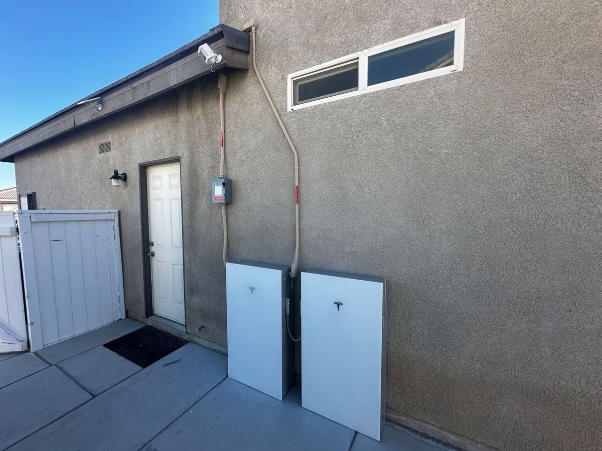 Two whole-home battery backup units mounted on a house wall