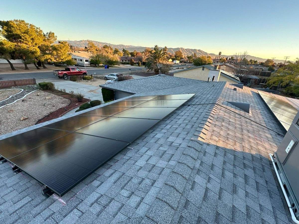 Rooftop solar panels on a shingled roof at sunset