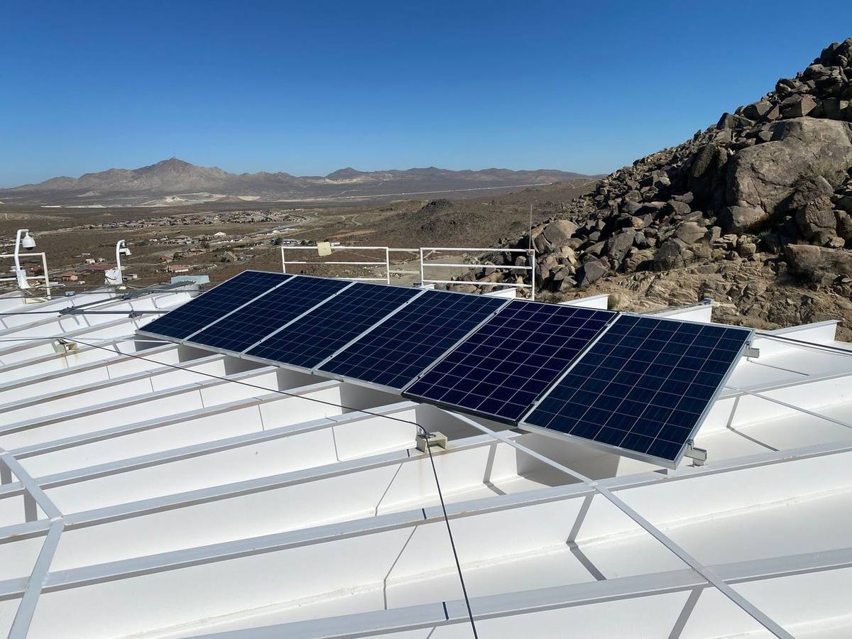 Solar panels on a white rooftop with desert mountains behind it